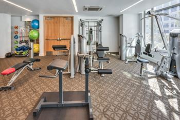 A gym with a variety of equipment including a treadmill, weights, and exercise machines.